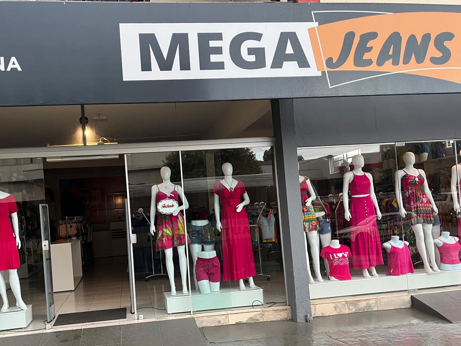 Fachada de uma loja de moda feminina, com vitrines e duas antenas antifurto de acrílico na porta