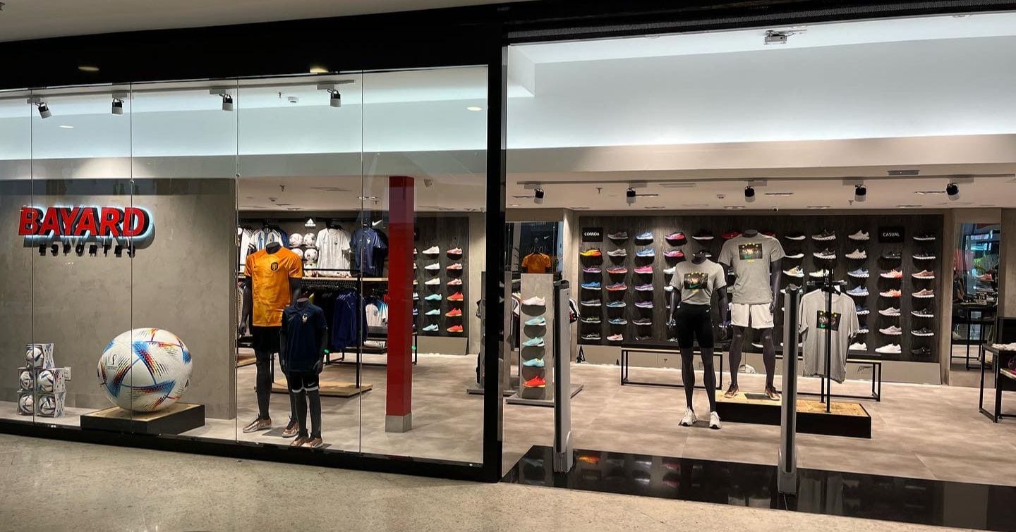 Vitrine de loja de artigos esportivos com roupas, calçados e pedestais antifurto